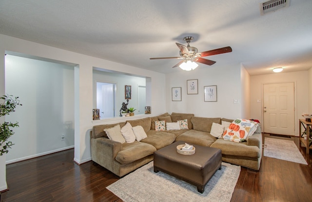 living room with a textured ceiling, ceiling fan, and dark hardwood / wood-style flooring