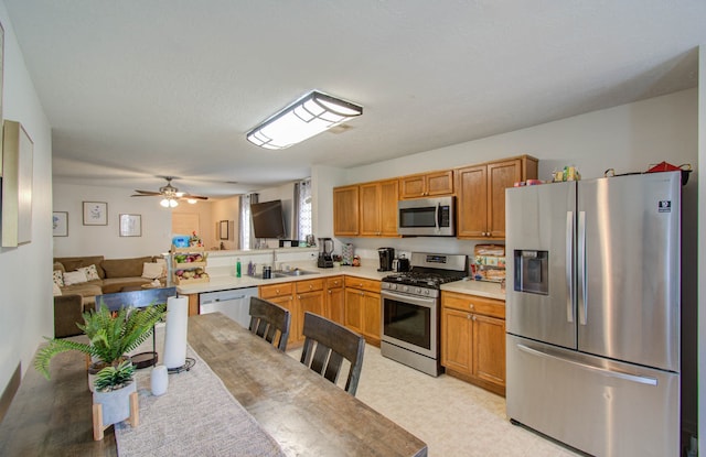 kitchen featuring kitchen peninsula, sink, ceiling fan, and stainless steel appliances