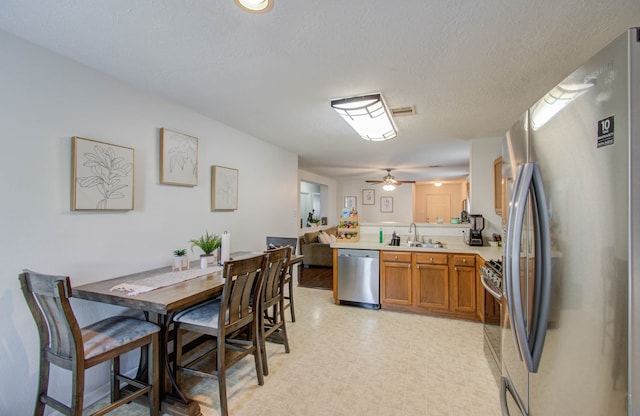 dining area featuring a textured ceiling, sink, and ceiling fan