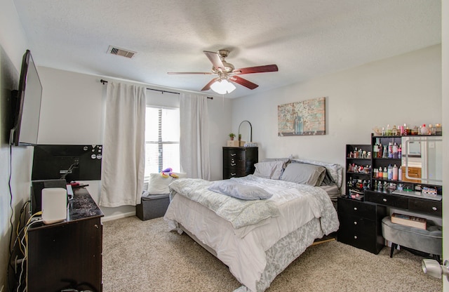 carpeted bedroom featuring a textured ceiling and ceiling fan