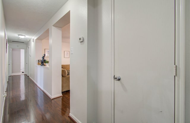 hall featuring a textured ceiling and dark hardwood / wood-style flooring