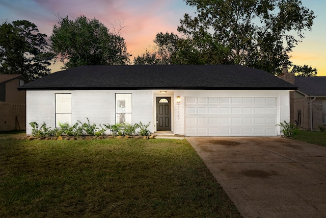 single story home featuring a lawn and a garage