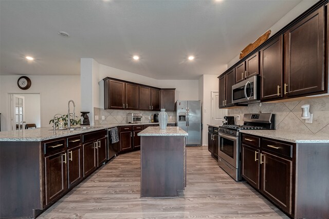 kitchen with a kitchen island, dark brown cabinetry, sink, light hardwood / wood-style flooring, and appliances with stainless steel finishes