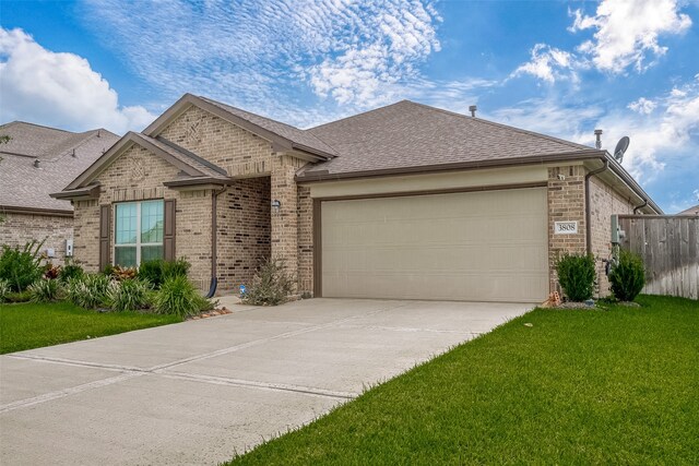 ranch-style house featuring a shingled roof, concrete driveway, an attached garage, a front lawn, and brick siding