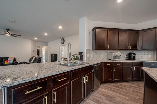 kitchen featuring light wood-type flooring, backsplash, sink, and stainless steel dishwasher