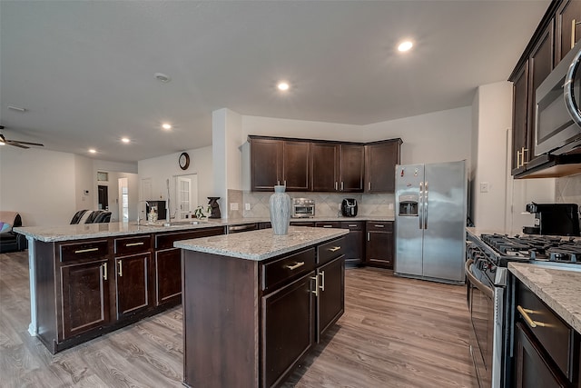 kitchen featuring kitchen peninsula, light wood-type flooring, a center island, and stainless steel appliances