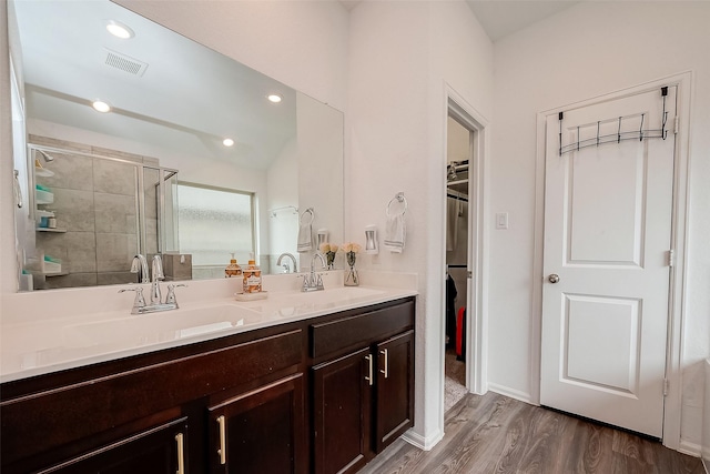 full bathroom featuring a shower stall, a spacious closet, visible vents, wood finished floors, and a sink