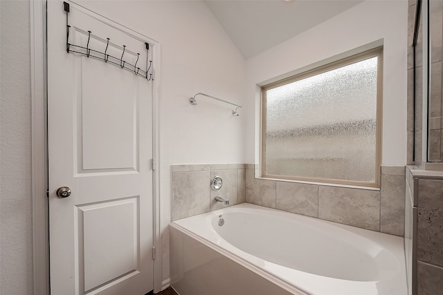 bathroom with a tub to relax in and vaulted ceiling