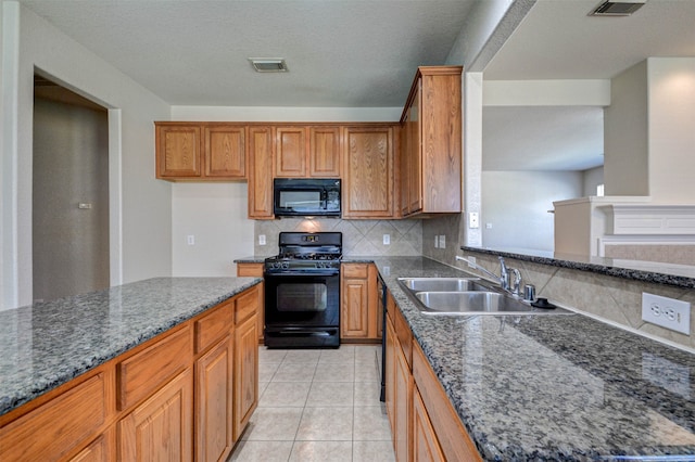 kitchen with sink, decorative backsplash, black appliances, light tile patterned floors, and dark stone countertops