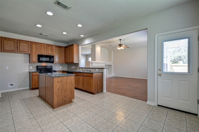 kitchen with ceiling fan, light tile patterned flooring, a center island, and black appliances