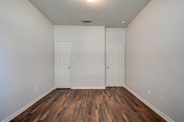 unfurnished room featuring a textured ceiling and dark wood-type flooring