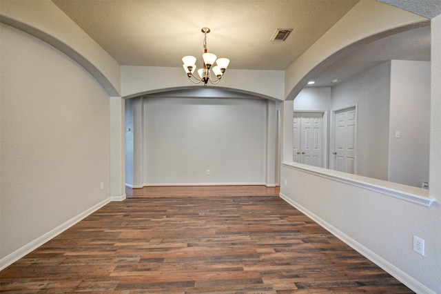 interior space with a textured ceiling, an inviting chandelier, and dark wood-type flooring