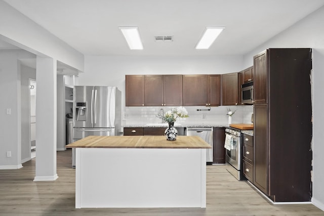 kitchen featuring appliances with stainless steel finishes, decorative backsplash, a center island, light hardwood / wood-style flooring, and dark brown cabinetry