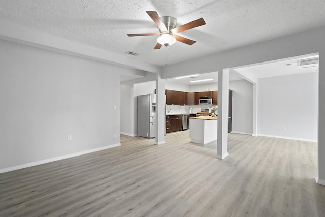 unfurnished living room featuring light hardwood / wood-style floors, ceiling fan, and a textured ceiling