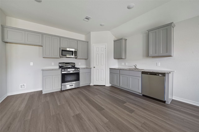 kitchen with gray cabinetry, dark hardwood / wood-style flooring, stainless steel appliances, lofted ceiling, and sink