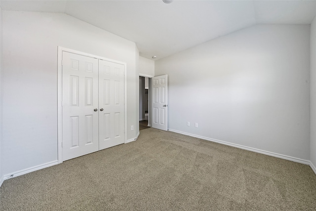 unfurnished bedroom with carpet flooring, lofted ceiling, and a closet