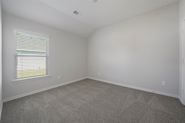 spare room with dark colored carpet and lofted ceiling