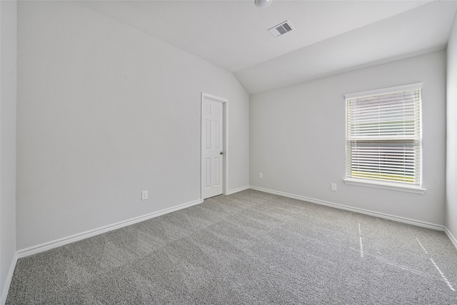 carpeted empty room featuring vaulted ceiling