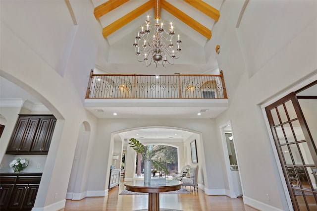 entrance foyer featuring light hardwood / wood-style floors, an inviting chandelier, beam ceiling, and high vaulted ceiling