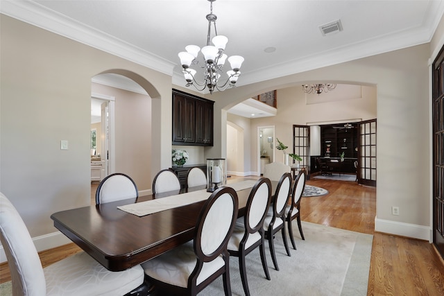 dining area featuring a notable chandelier, ornamental molding, french doors, and light wood-type flooring