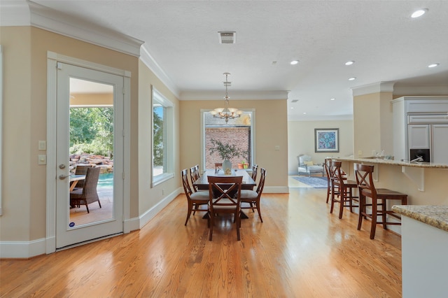 dining room with crown molding, a notable chandelier, a textured ceiling, and light hardwood / wood-style floors