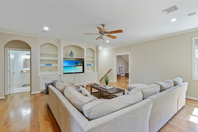 living room with ornamental molding, built in features, and light hardwood / wood-style floors