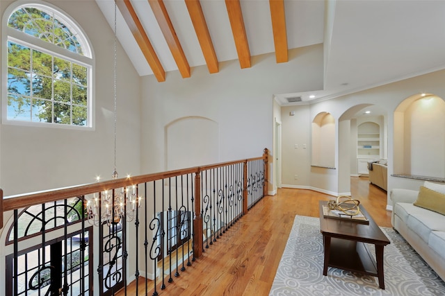 hallway with an inviting chandelier, beamed ceiling, light wood-type flooring, and high vaulted ceiling