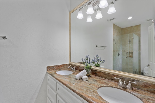 bathroom with a shower with door, vanity, and toilet