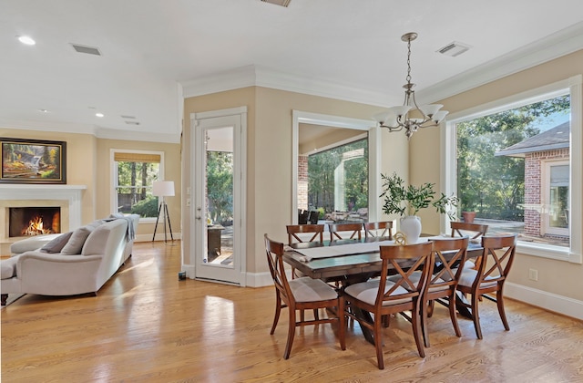 dining space featuring light hardwood / wood-style floors, crown molding, a healthy amount of sunlight, and a notable chandelier