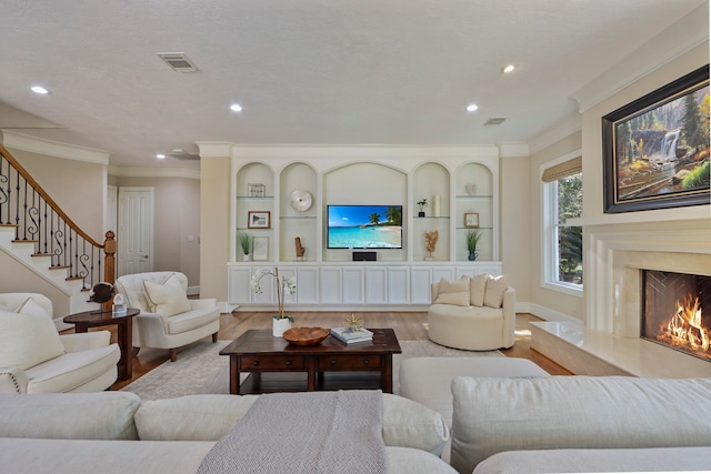 living room with light hardwood / wood-style floors, ornamental molding, and a fireplace