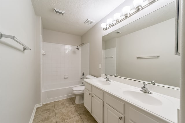 full bathroom featuring tile patterned flooring, a textured ceiling, vanity, tiled shower / bath, and toilet