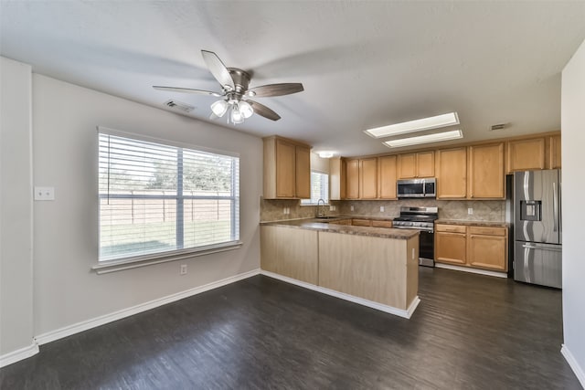 kitchen featuring sink, kitchen peninsula, tasteful backsplash, dark wood-type flooring, and stainless steel appliances