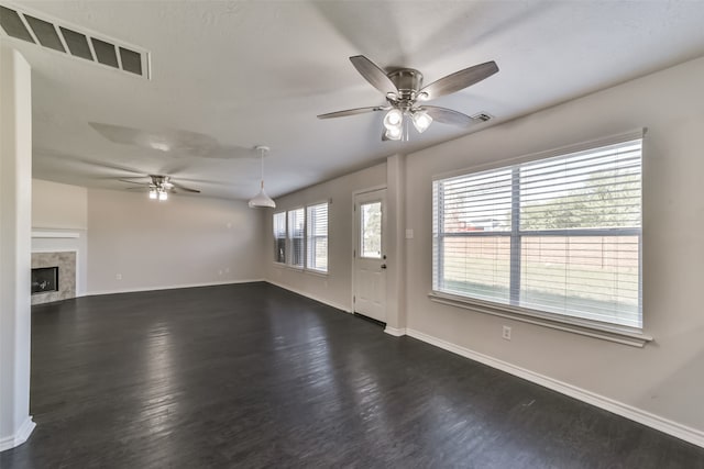 unfurnished living room with a high end fireplace, ceiling fan, and dark wood-type flooring