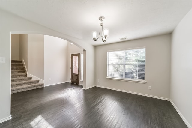 spare room featuring a chandelier and dark hardwood / wood-style flooring