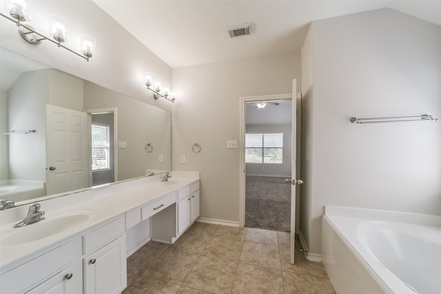 bathroom featuring tile patterned floors, vaulted ceiling, vanity, and a bathing tub