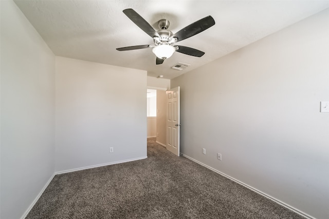 spare room with dark colored carpet and ceiling fan