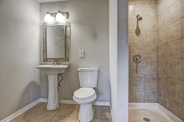 bathroom with tile patterned flooring, toilet, and tiled shower