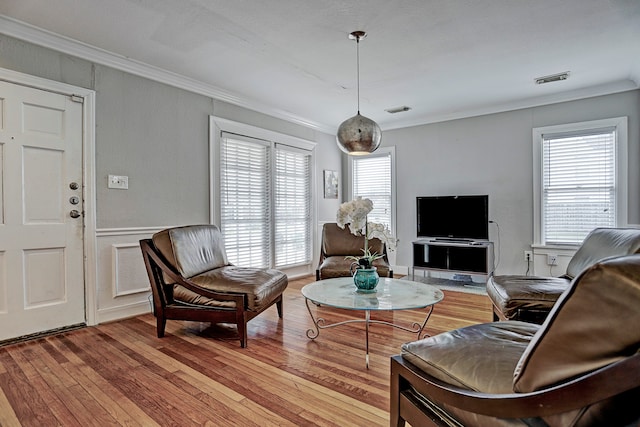 living room featuring light wood-type flooring, plenty of natural light, and ornamental molding