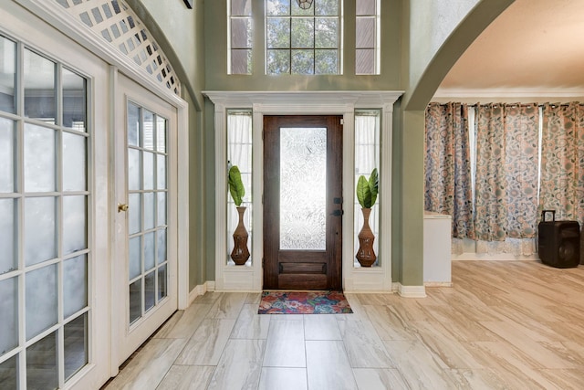 foyer with ornamental molding, a wealth of natural light, and a high ceiling