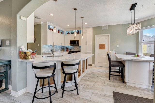 kitchen with a textured ceiling, a breakfast bar area, sink, and decorative light fixtures