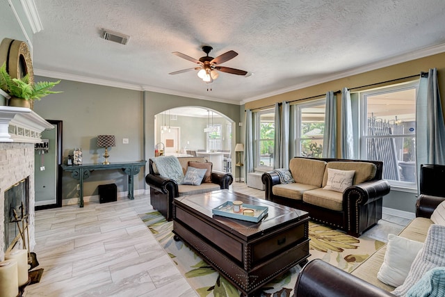 living room featuring a stone fireplace, a textured ceiling, and crown molding