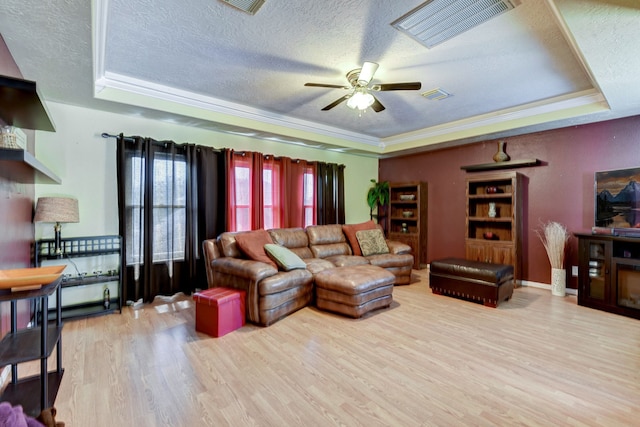 living room featuring a textured ceiling, light wood-type flooring, and a raised ceiling