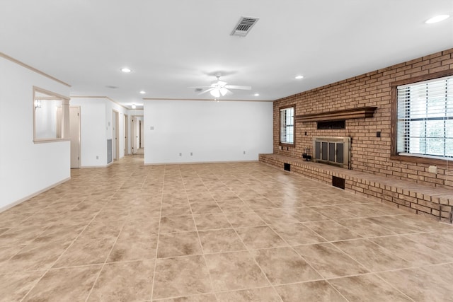 unfurnished living room with a fireplace, ornamental molding, ceiling fan, and brick wall