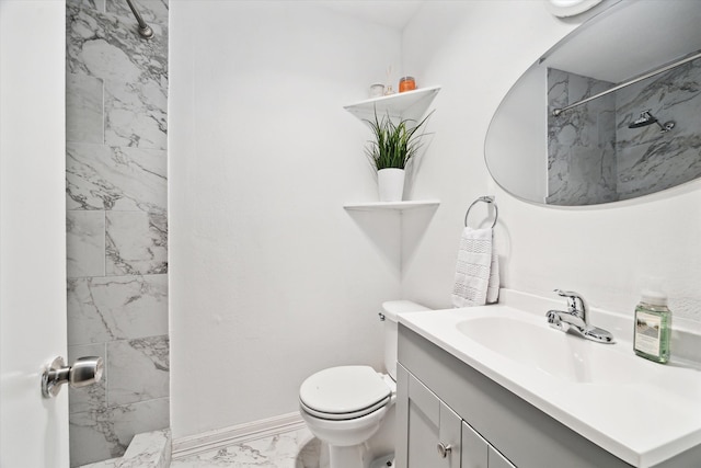 bathroom with a tile shower, vanity, and toilet