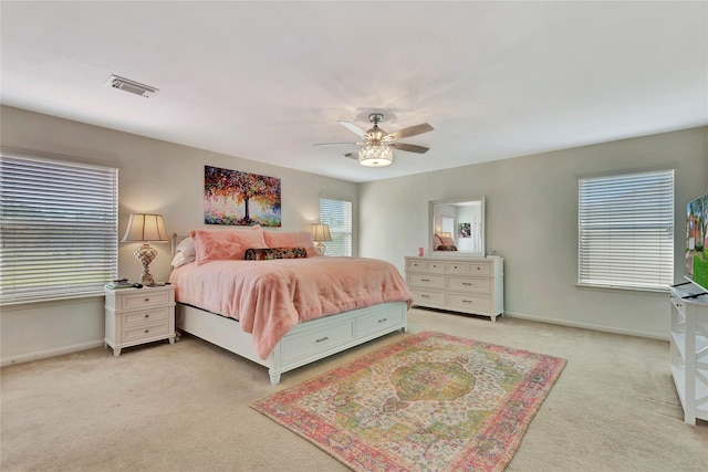 bedroom with multiple windows, ceiling fan, and light carpet