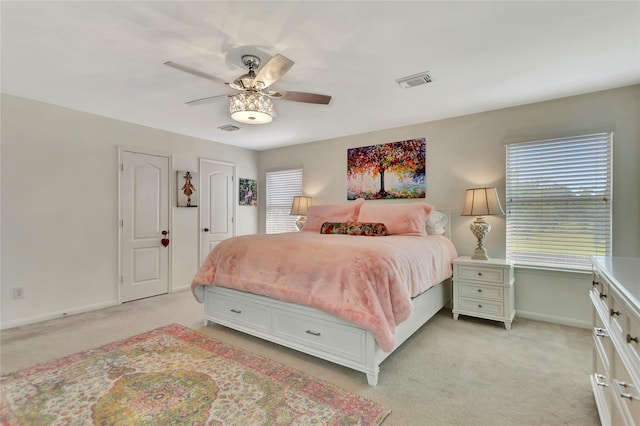 bedroom featuring ceiling fan, light colored carpet, and two closets