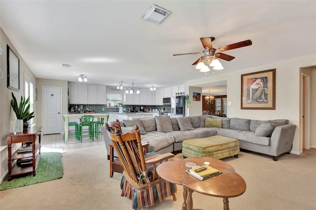 living room featuring ceiling fan with notable chandelier, light carpet, and a wealth of natural light