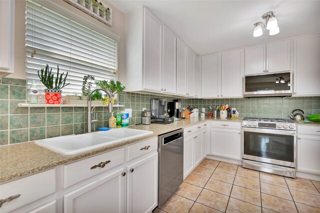 kitchen with white cabinets, appliances with stainless steel finishes, tasteful backsplash, and sink