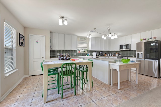 kitchen with pendant lighting, a healthy amount of sunlight, a breakfast bar, and stainless steel appliances