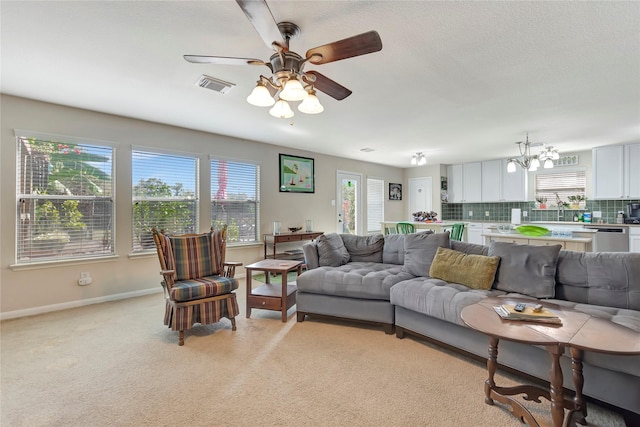 carpeted living room featuring ceiling fan with notable chandelier